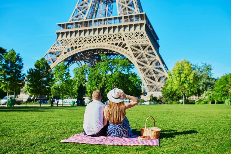 The 10 Best Spots for a Picnic in Paris A couple having a picnic near the Eiffel Tower