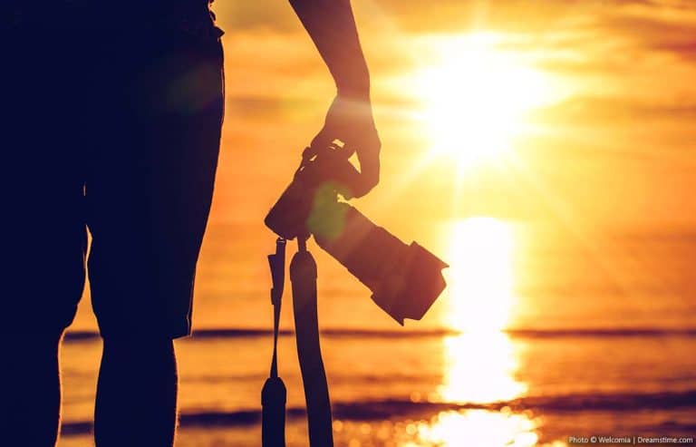 How to Choose the Perfect Travel Camera Photography holding a camera at sunset
