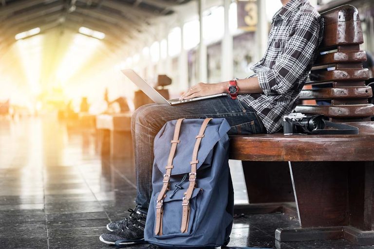 Why Blogging and Photography is Great For Travellers man on a laptop in an airport